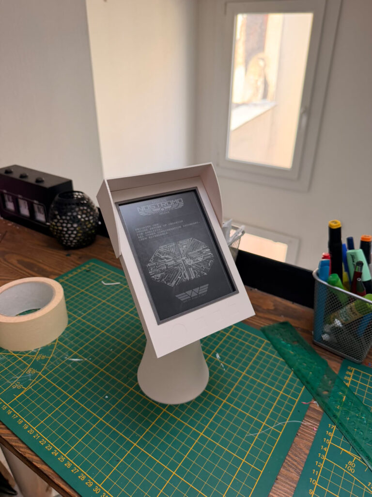 Prototype blanc du support Nostrum sur un tapis de découpe dans l'atelier du studio QALC